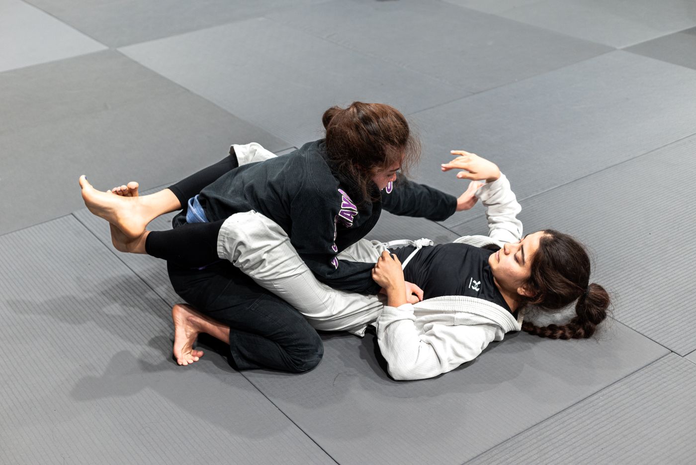 Two jiu-jitsu practitioners training together on the mats