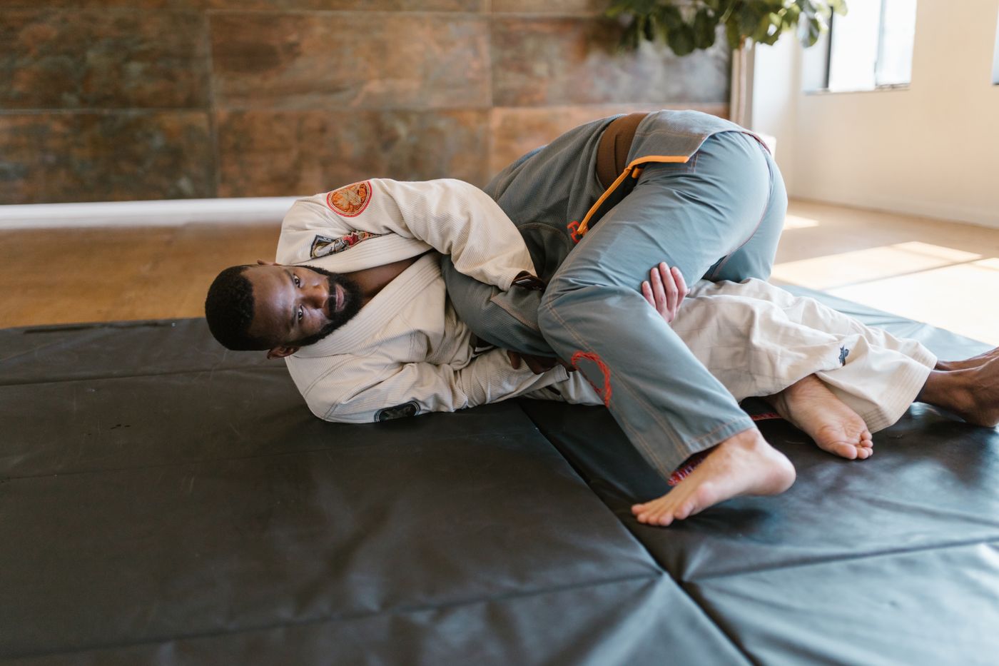 Two jiu-jitsu practitioners rolling at a gym